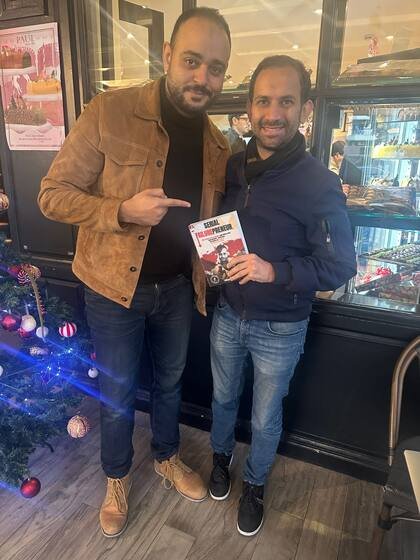 Deux lecteurs avec le livre devant une boulangerie
