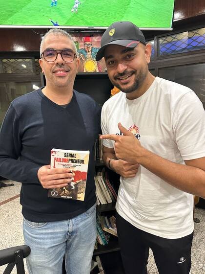 Un lecteur tient le livre devant une bibliothèque de café